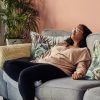 Fatigued woman with fibromyalgia on sofa.