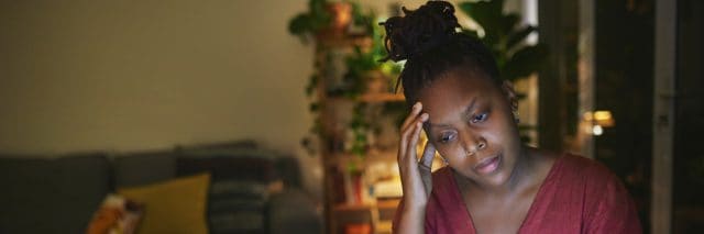 Black woman sitting at home working, stressed