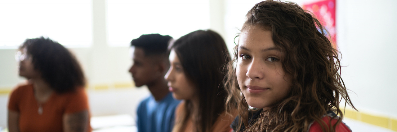How Emotional Intelligence Sex Ed Could Be a Game Changer Portrait of a female teenage student in classroom, with a group of diverse students beside her