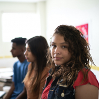 Portrait of a female teenage student in classroom, with a group of diverse students beside her