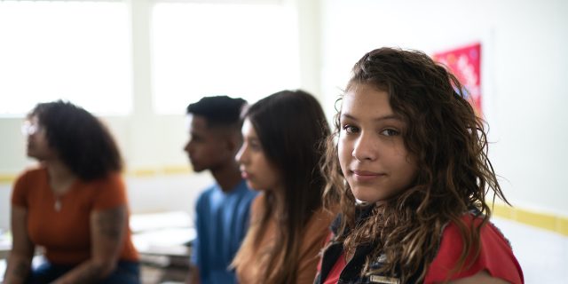 How Emotional Intelligence Sex Ed Could Be a Game Changer Portrait of a female teenage student in classroom, with a group of diverse students beside her