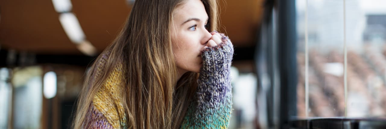 Mental Health Relapse Prevention Plan: What It Is and How to Make One photo of a woman sitting at a table looking out of a window, thoughtful
