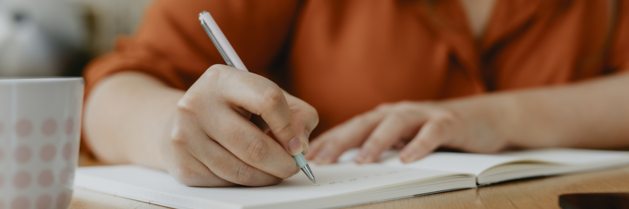 Deleting Your Menstrual Cycle Tracking App After Roe v. Wade? Try These Printables Instead photo of a woman writing in a journal