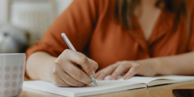 Deleting Your Menstrual Cycle Tracking App After Roe v. Wade? Try These Printables Instead photo of a woman writing in a journal