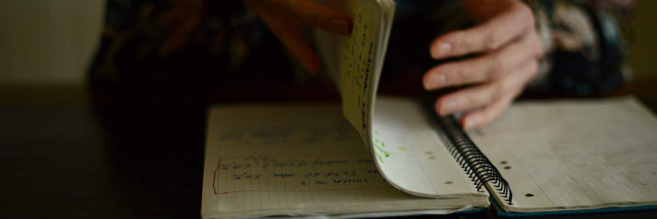 How Writing a Letter to People Who Are Suicidal Changed My Life a woman writing in a notebook with a green pencil