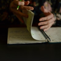 a woman writing in a notebook with a green pencil