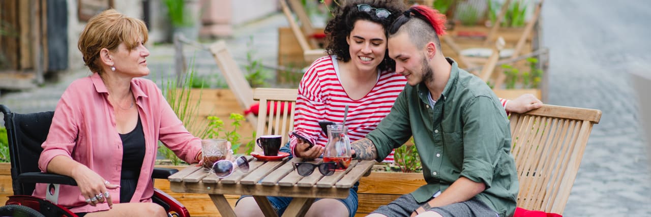 How to Make a Restaurant Accessible to Customers With Disabilities Disabled people with friend sitting outdoors in cafe.