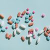 Colorful pills and capsules on blue background.