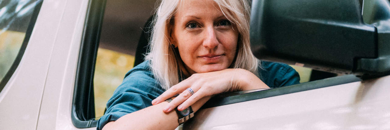 photo of a woman leaning out of her car looking at the camera