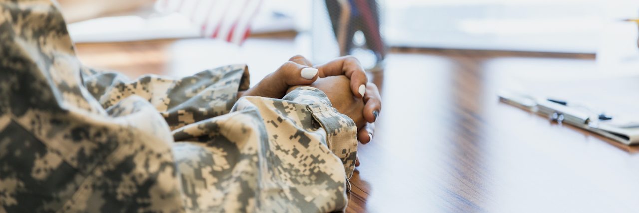 A Significant Step in Helping Veterans This 4th of July  Close up of Black woman who is wearing a camouflage uniform arms and hands on a desk, with small flag behind them