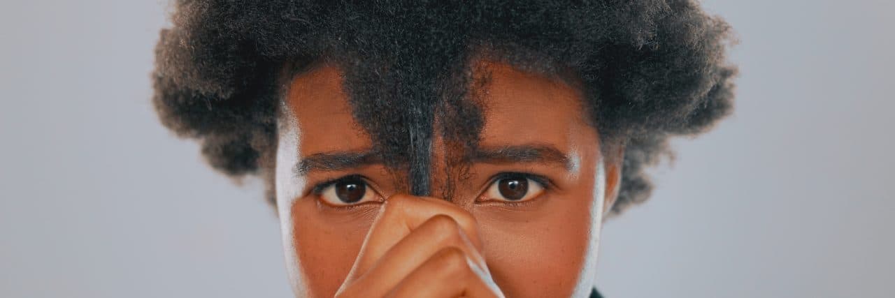 Why One Woman Wants to Relax Her Hair Due to ADHD A black woman stares at the camera holding her natural hair in her hand with an inquisitive look on her face