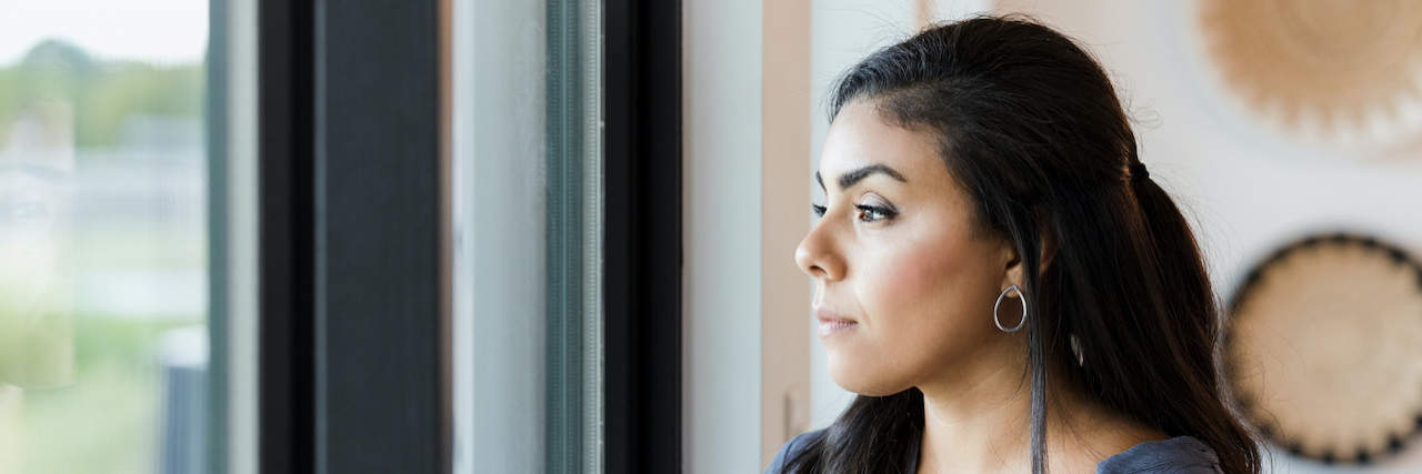 My Experience With the 'Walking Corpse' Delusion, Cotard's Syndrome Woman of color stands holding a mug and looking out window