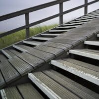Section of a wooden stairway with steep ramp leading over the dunes towards the beach.