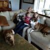 Mother and daughters sitting on sofa with pets dogs, watching TV together.