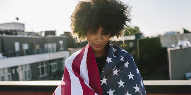 Sad woman wrapped in American flag.