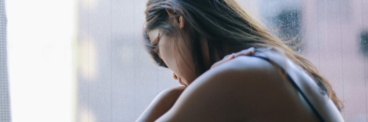 photo of a woman looking upset in front of a window