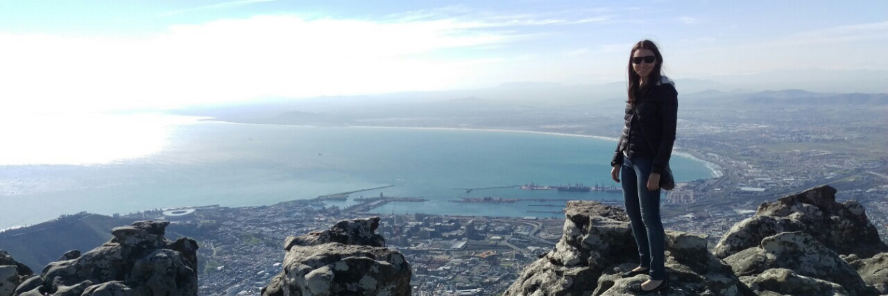 Taking Back Our Power in Life With Chronic Illness Woman standing on mountaintop