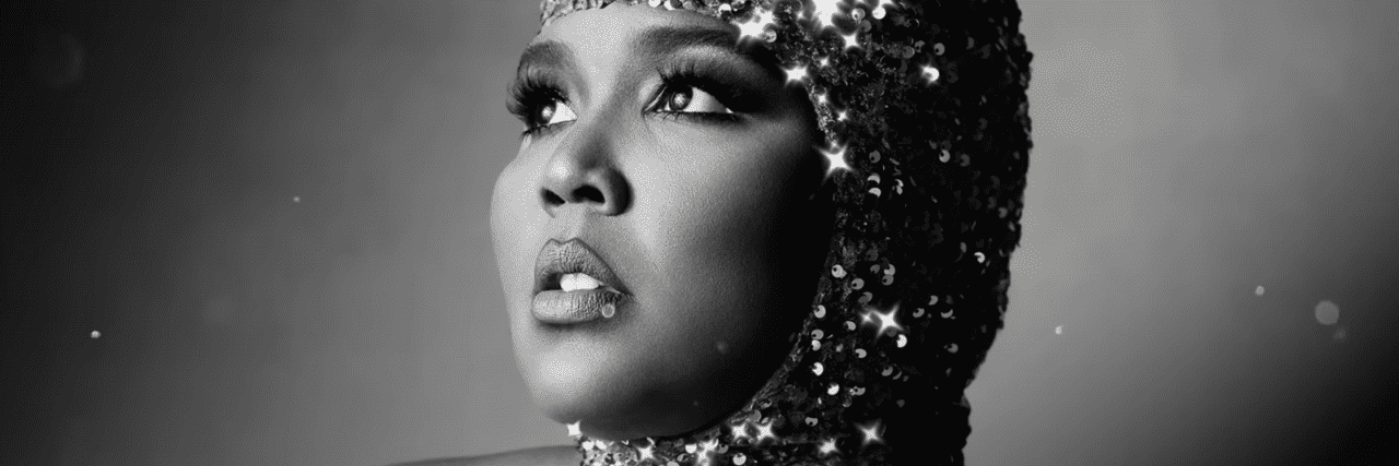 Lizzo looking off into the distance with a sparkly shimmery headpiece