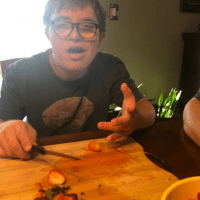 George, a teen with Down syndrome, cutting strawberries.