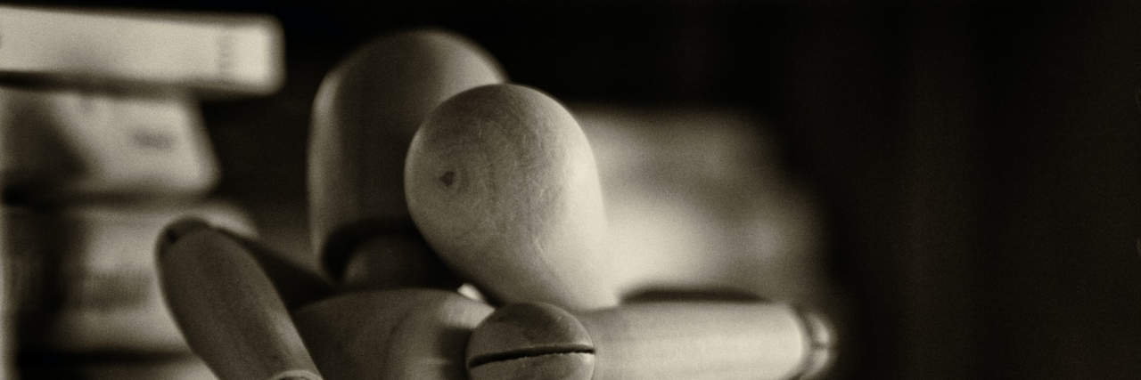 How to Cope With the Distress of a Fibromyalgia Flare-Up Two wooden figures embracing.