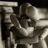 Two wooden figures embracing.