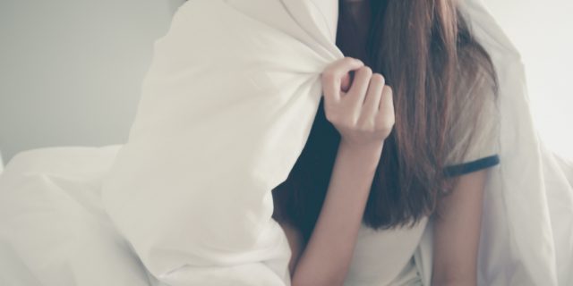 Woman hiding her head in her pillow.