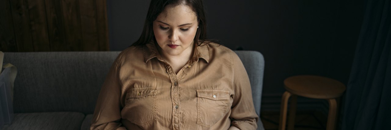 I'm a Health Writer, But It's OK That I Struggle to Take Pride in My Heath Conditions A woman with brown hair looks at her laptop and types.