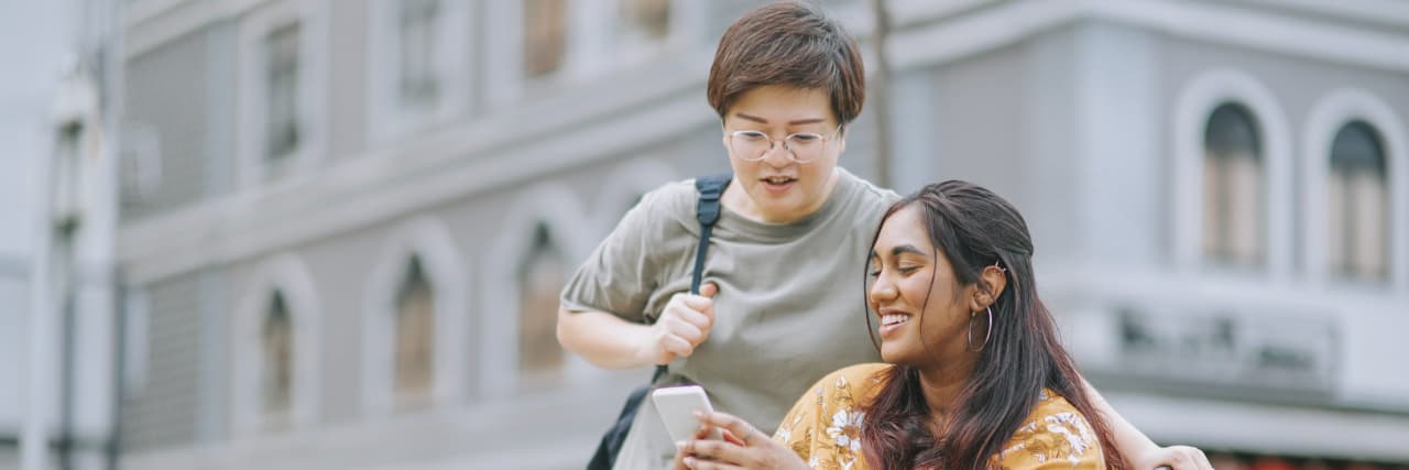 Accepting People With Disabilities as Valuable to the Community A woman in a wheelchair outside of a building chats with another woman.
