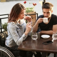 Disabled young woman and her boyfriend in a cafe. Both about 25 years old, Caucasian people.