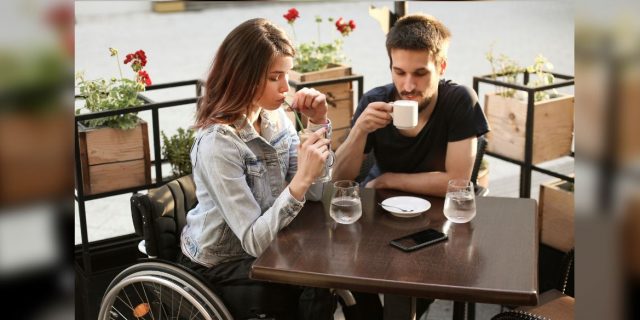Disabled young woman and her boyfriend in a cafe. Both about 25 years old, Caucasian people.