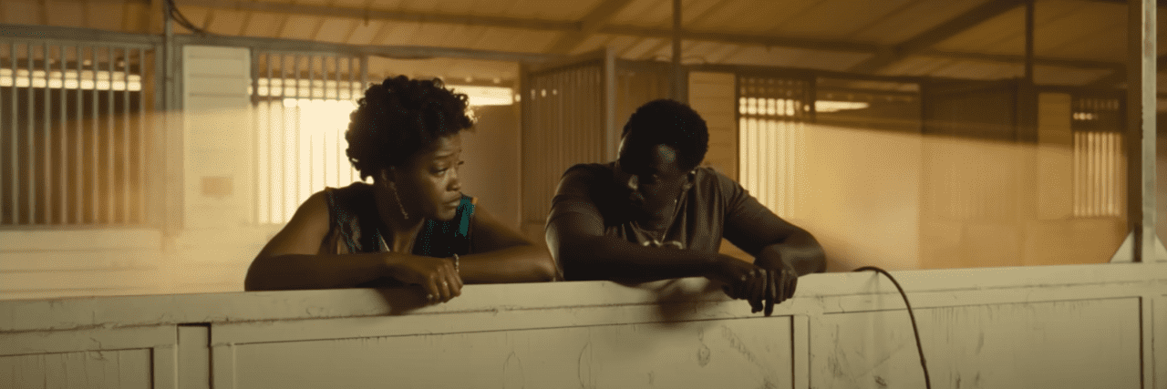 Exploring Grief as a Major Theme in Jordan Peele's 'Nope' OJ and Em from the movie "NOPE" looking back at one another in a horse stable.