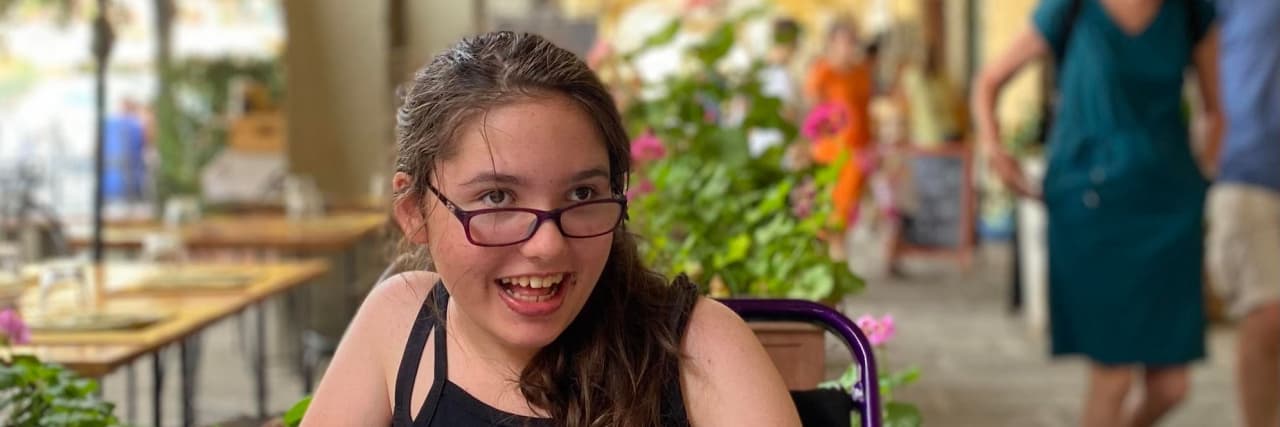 Why I Don't Mind Being Called Inspirational as a Teen With Cerebral Palsy Zoe sitting in an outdoor cafe.