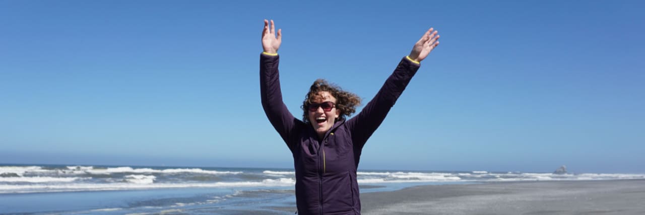 Redefining Strength in My Life With POTS Lindsay jumping for joy by the water.