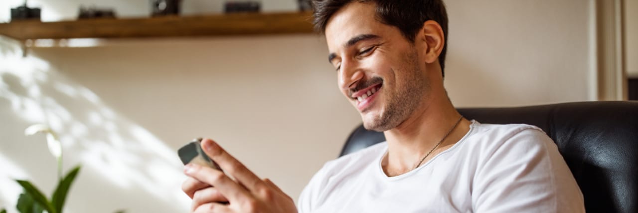 Encouraging Messages to Read If You’re Struggling With Depression Right Now photo of a man smiling and checking messages on his phone
