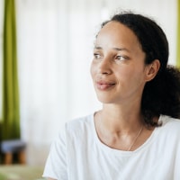 Woman of color at home looking to the side with a slight smile