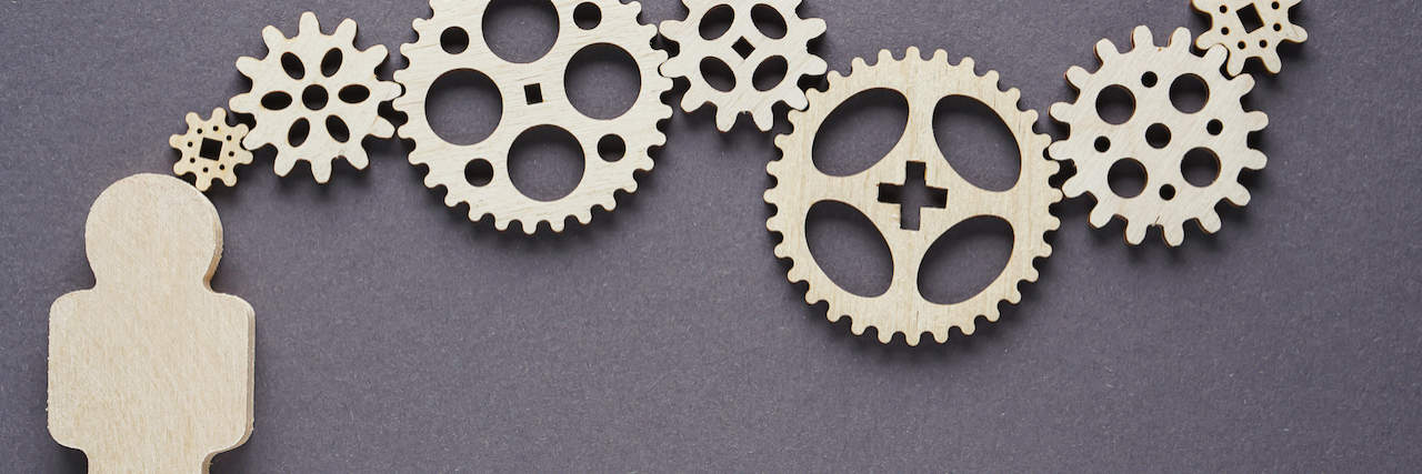 Abstract shape of person with gears on gray background