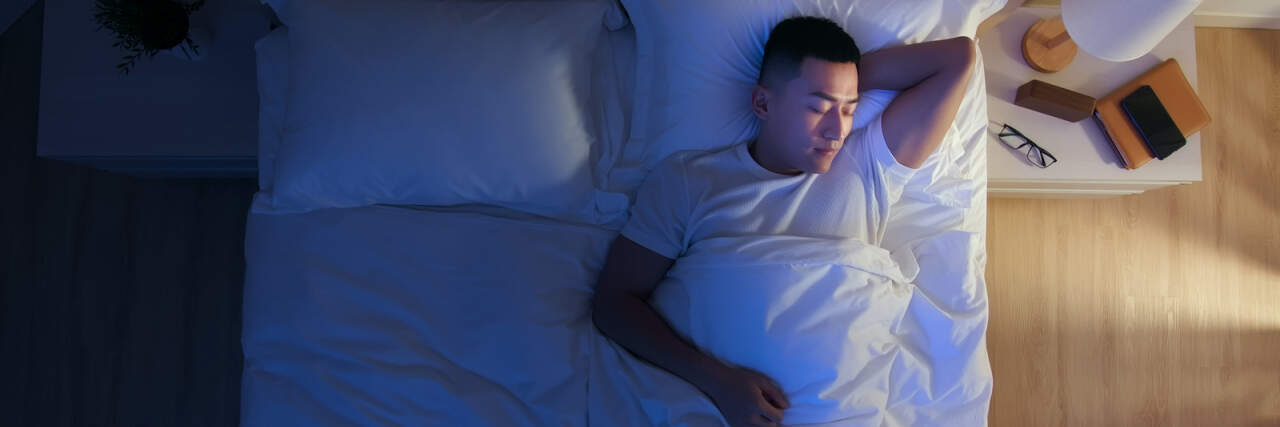 Top view of Asian man laying in bed at night sleeping
