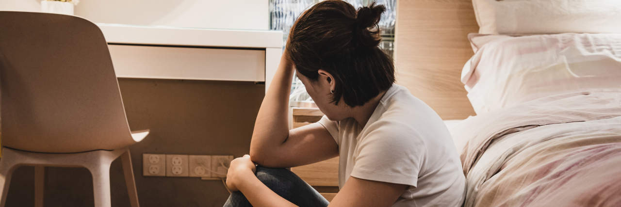 When Your Therapist Tells You They Can't Treat You Anymore Woman sitting against her bed, sad