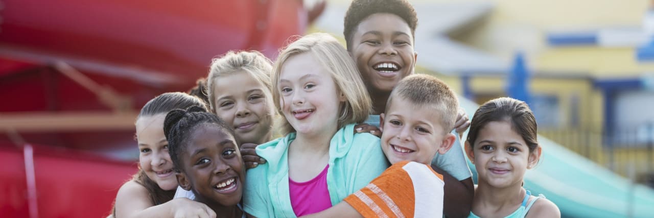 Why Social Skills Development Must Be Part of IEPs A 10 year old girl with down syndrome having fun at a water park, in the center of a multi-ethnic group of friends, getting a group hug.