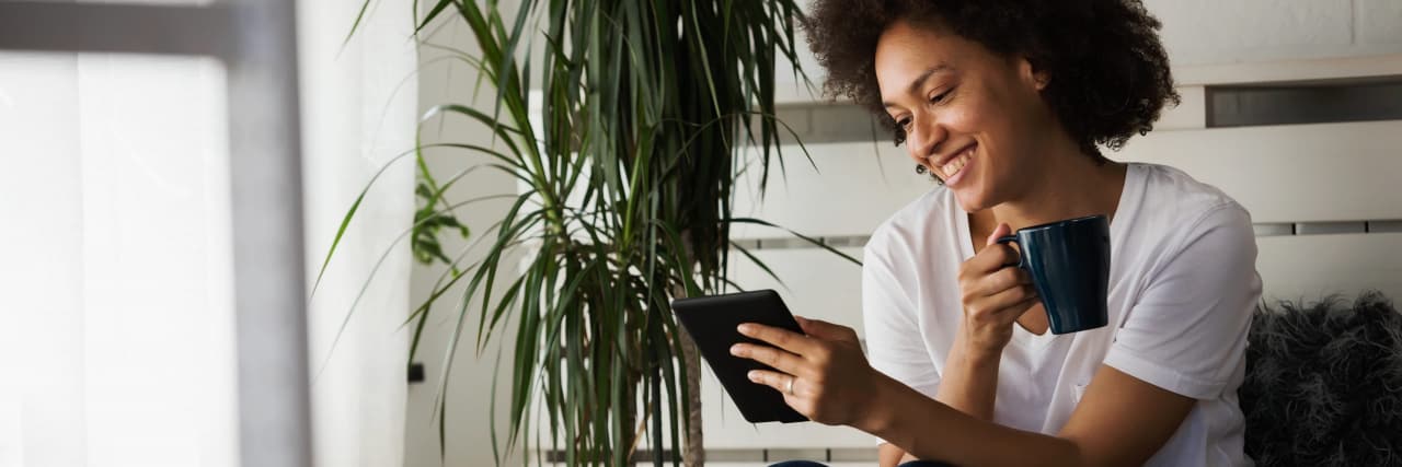 If You Struggle With Reading With ADHD, Try an E-Reader Pretty african american young woman reading an eBook at home at her cozy corner