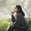 Thoughtful woman with dark hair sitting on bench