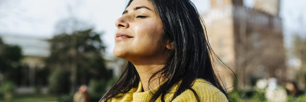 Why Using Someone’s Correct Gender Pronouns Is Important for Their Mental Health photo of a person hugging themselves in sunlight