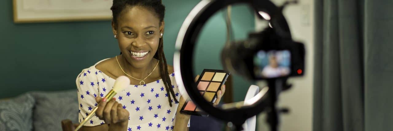 The Dangers of Turning Your ADHD Hyperfixations Into Your Career Young Black woman filming a beauty and makeup vlog