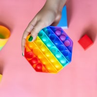 photo of a person'a hand holding a rainbow-colored pop-it