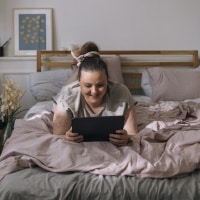 Woman watching movie on tablet in bed.