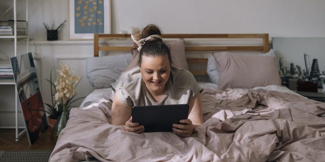 Woman watching movie on tablet in bed.