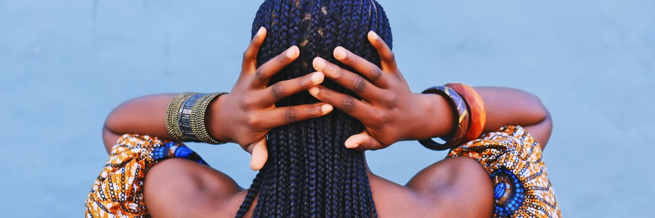 ADHD-Friendly Protective Styles for Black Hair Rearview shot of a young woman wearing traditional African clothing and feeling her hair against a blue background