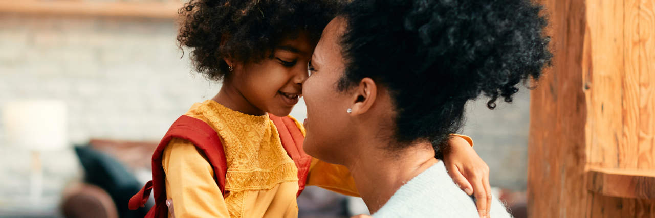 photo of a mother and daughter on first day of school, holding her to comfort her