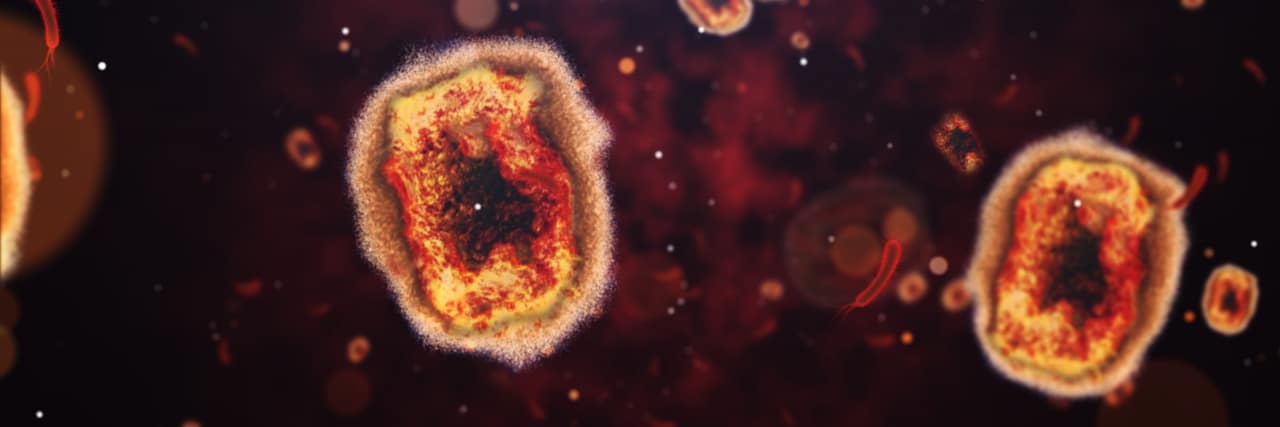 Here's What You Need to Know About Monkeypox Against a dark background is some red monkeypox virus cells