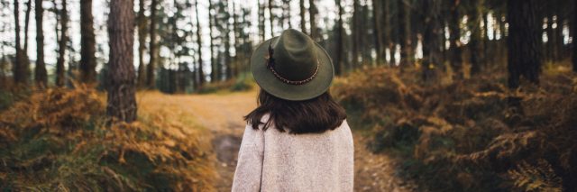Woman with hat walking in the woods.